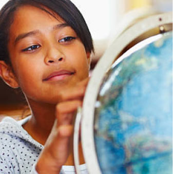 A young person with darker tan skin looks at a globe.