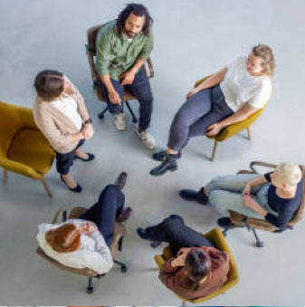 Overhead view of a support group of 6 adults sitting together indoors. 