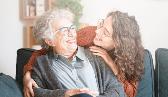 A woman with brown hair smiles at an older woman with white hair.