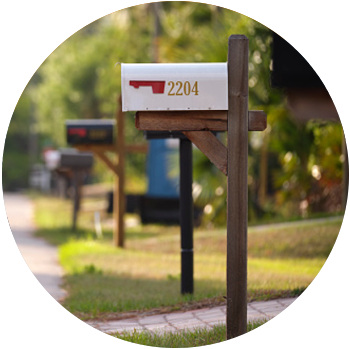 Multiple mailboxes line a suburban street. A white mailbox with a red handle is in focus.