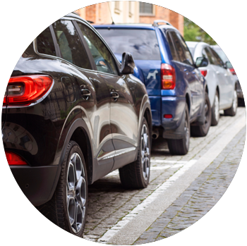 A crowded row of cars are parked the street in close proximity to one another.