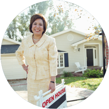 A tan middle-aged female real estate agent holds a sign that says Open House in front of a house.